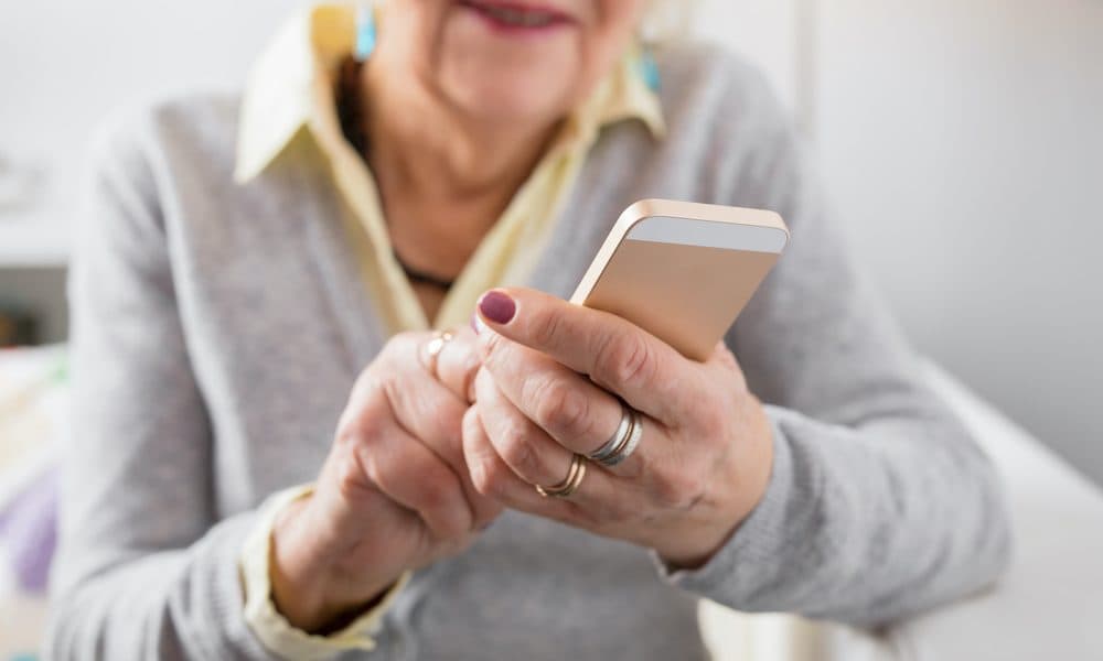 Senior,Woman,Holding,Smartphone COMMENT: Technology in care will have a double dividend for the NHS