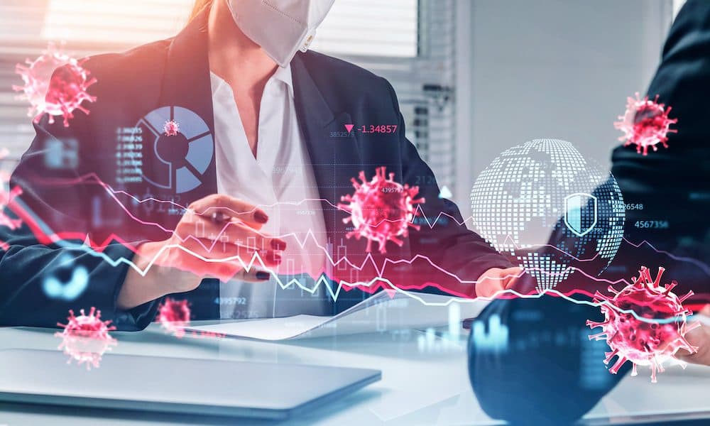 Businesswoman and businessman wearing formal suits and masks read notes COVID uncertainty shows why workplace testing must be a priority recommendation for the CBI and FSB