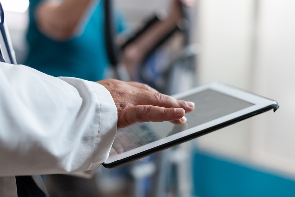 Close up of doctor using digital tablet with touch screen PASS by everyLIFE launches in Ireland with digital care management and AI-powered insights