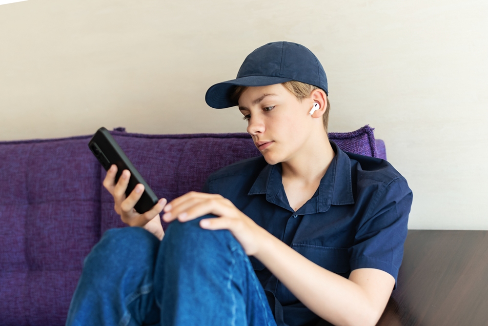 young-man-using-mobile-phone Teen boys using personalised AI for therapy, research finds